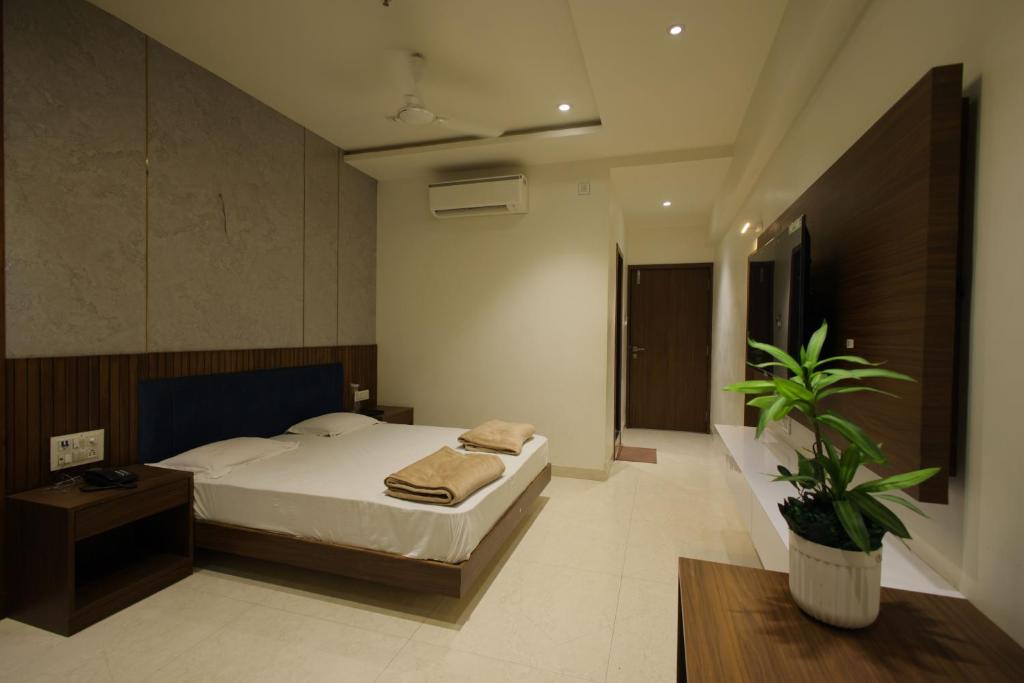 a bedroom with a bed and a potted plant at Hotel Shubhkarta in Akola