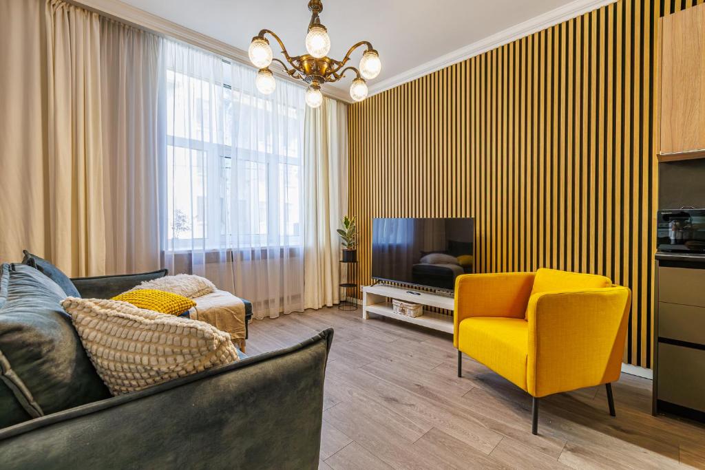 a living room with a yellow chair and a television at Amber Apartment in Riga