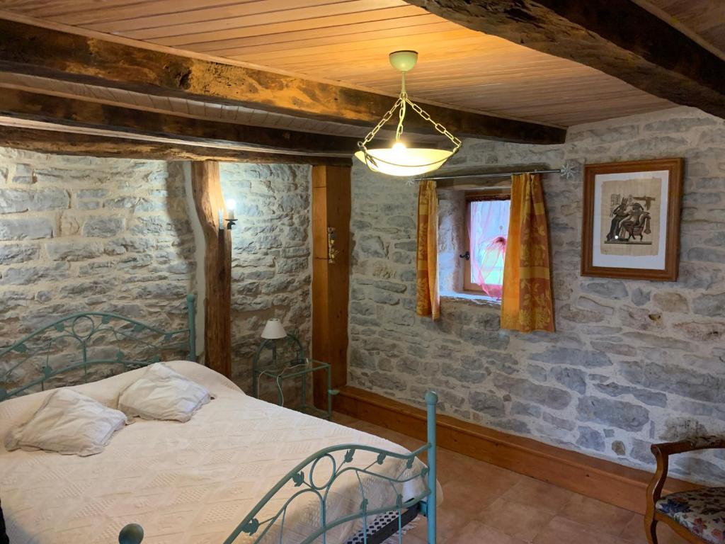 une chambre avec un lit et un mur en pierre dans l'établissement Mas d'Ambayrac chambres d'hôte Le bolet, à Promilhanes