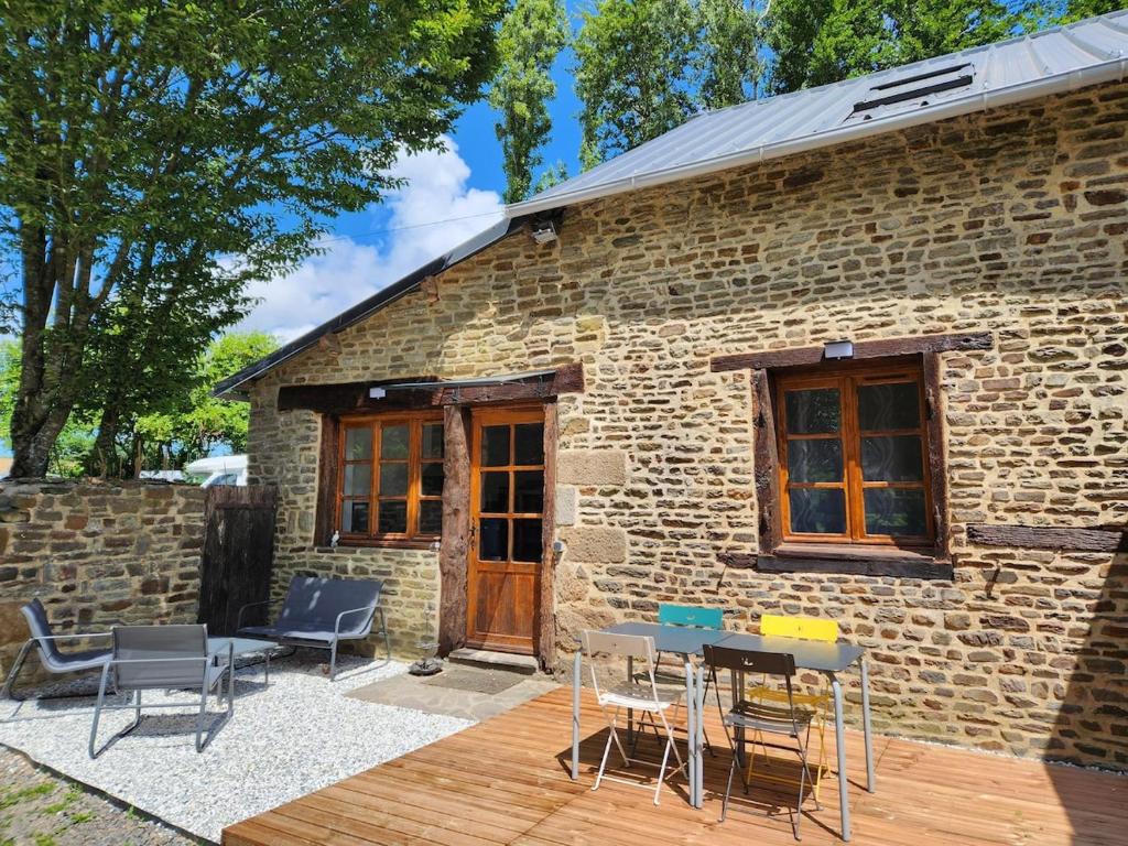 un bâtiment en briques avec des chaises et des tables devant lui dans l'établissement La Ferme Saint Jean, à Pontorson