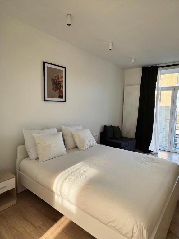 a large white bed in a room with a window at Bora Apartment in Brussels