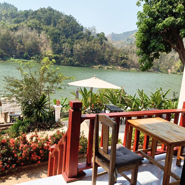 a table and chairs on a deck with a view of a river at Nam ou view villa in Nongkhiaw