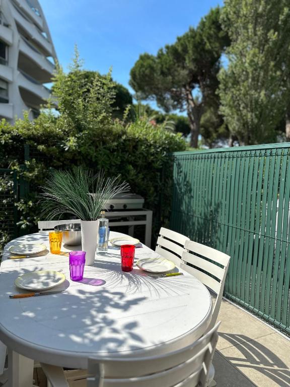 - une table blanche avec des assiettes et des tasses sur une terrasse dans l'établissement Les pins d'azur, à La Grande Motte