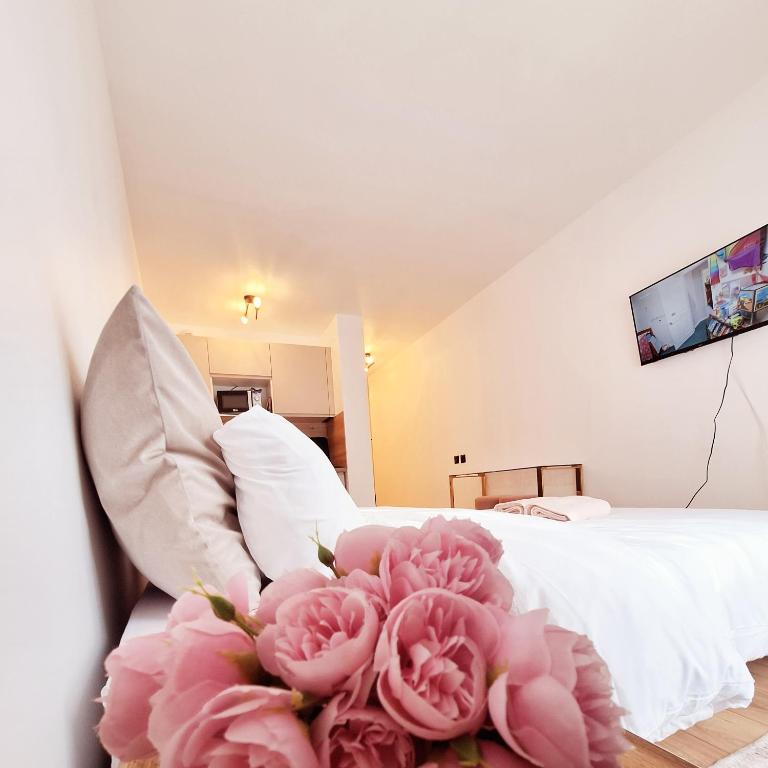 - une chambre avec un lit et un bouquet de fleurs roses dans l'établissement Studio FANTASIA with private car-park - 15min to Disneyland by city bus Number 2233, à Montévrain