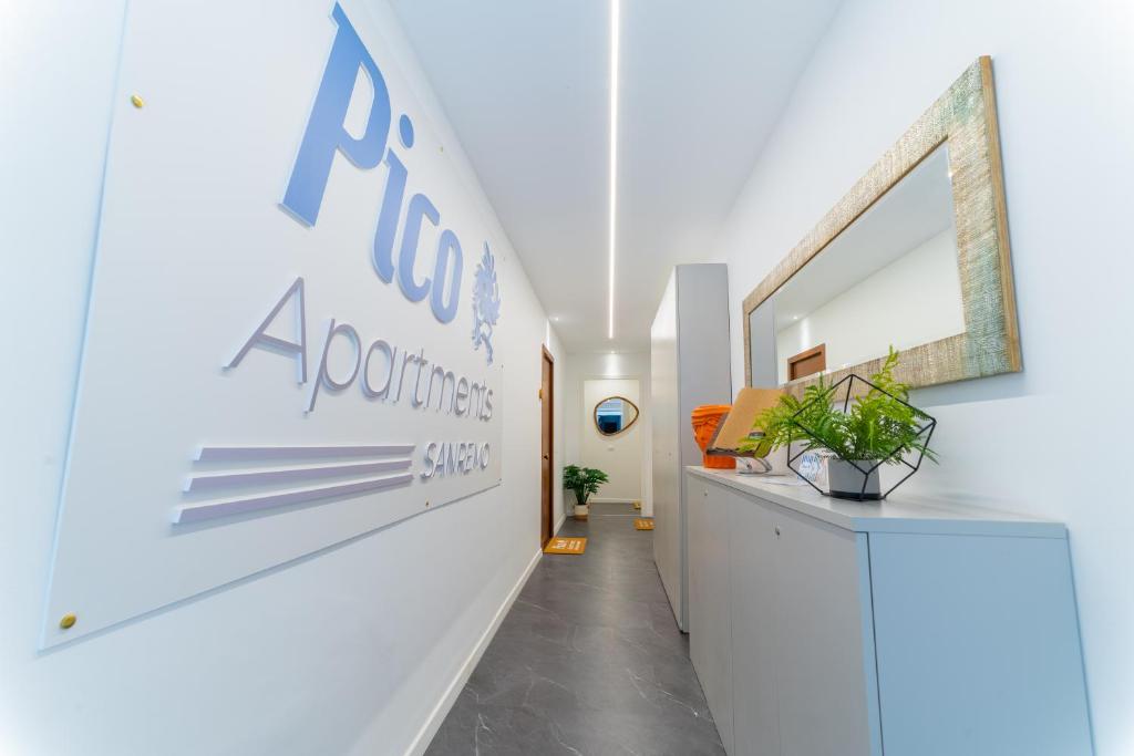 a hallway with a white wall with a sign on it at Pico Apartments - Roma 20 in Sanremo