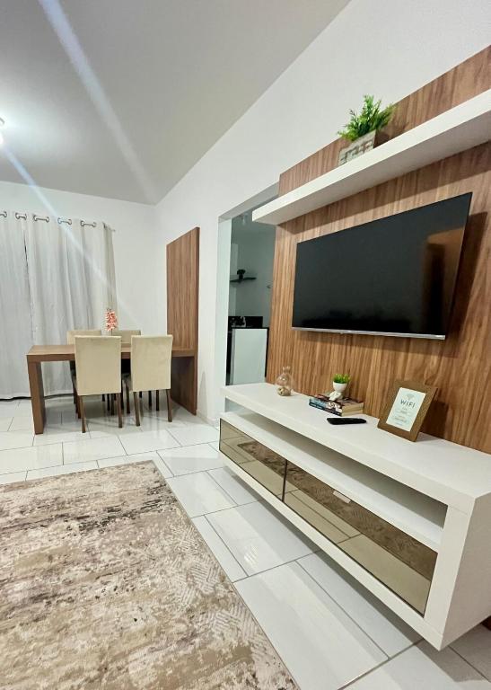 a living room with a large television and a table at Apê Conforto in Brusque