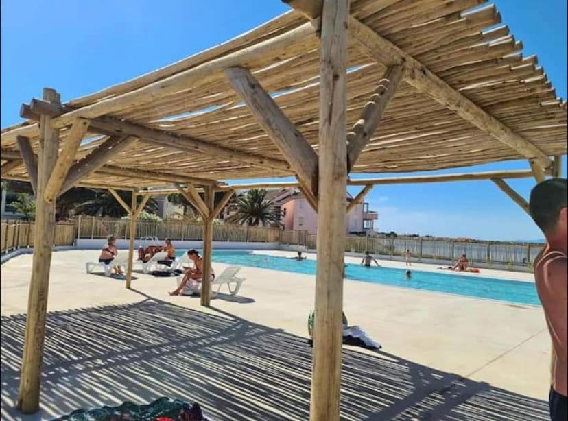 une pergola en bois à côté d'une piscine dans l'établissement Appartement dans résidence piscine chauffée, au Barcarès