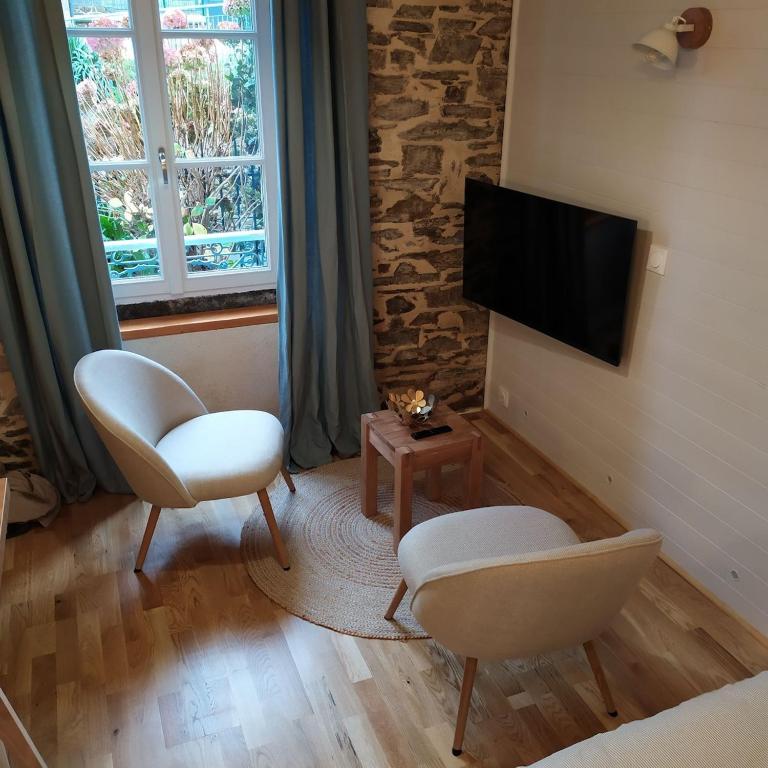 - un salon avec deux chaises et une télévision à écran plat dans l'établissement STUDIO HORTENSIA à 2 pas du port - Confortable, classé 2 étoiles, à Cancale