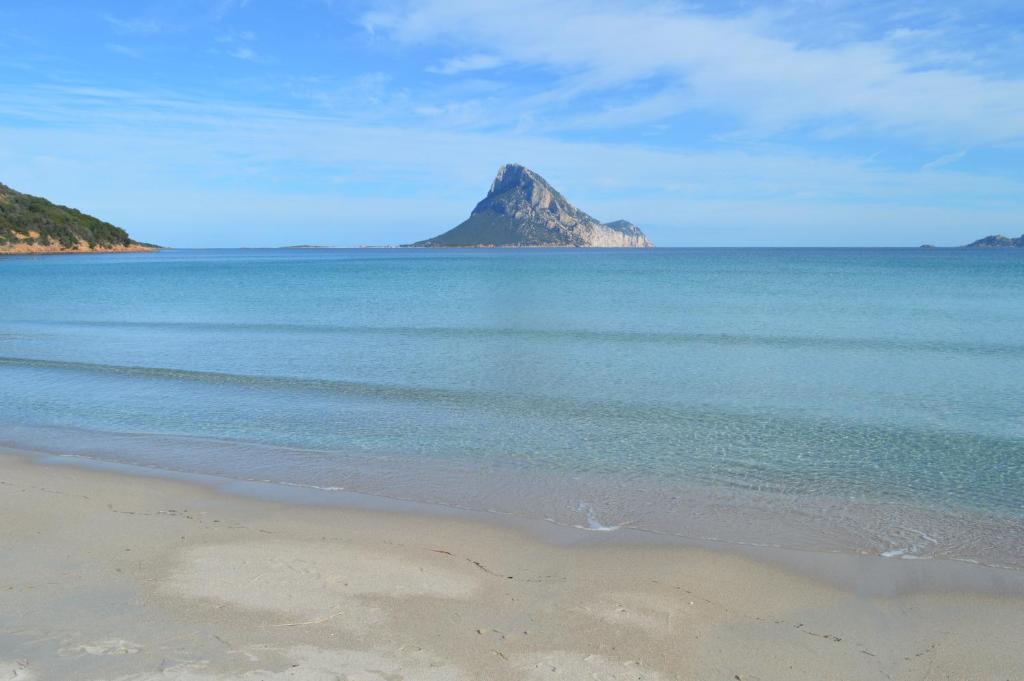 - une vue sur une plage avec une montagne au loin dans l'établissement Casa Lantana, à Porto Taverna
