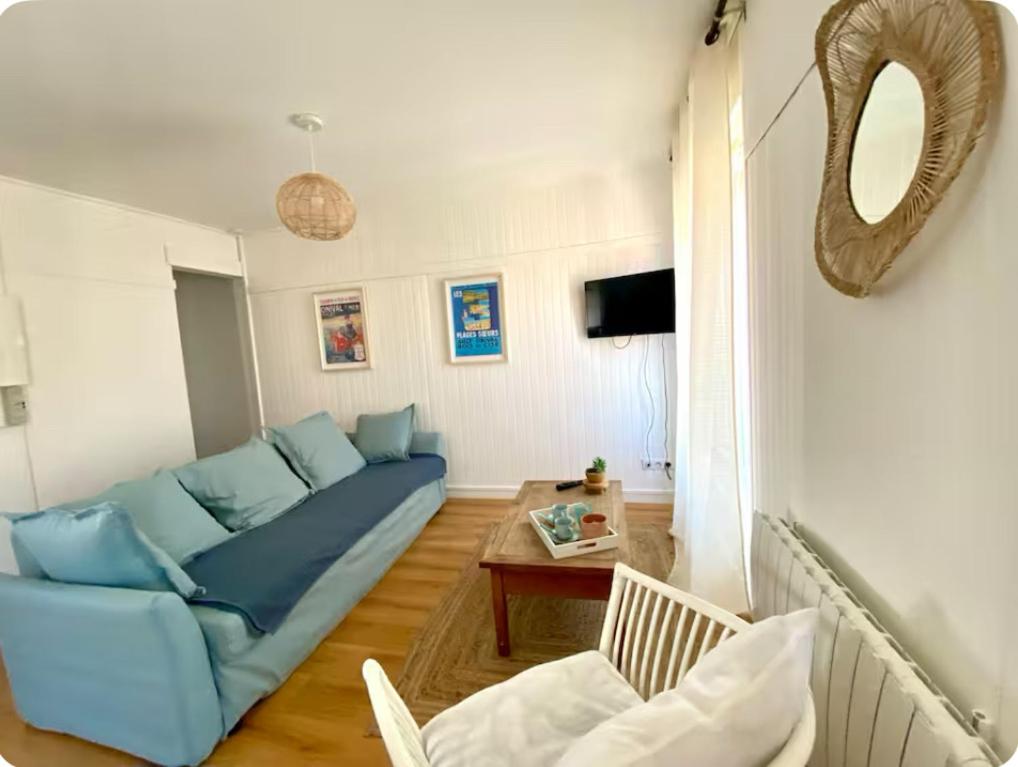 un salon avec un canapé bleu et une table dans l'établissement La Mouette Bleue -stationnement gratuit- mer, à Ault