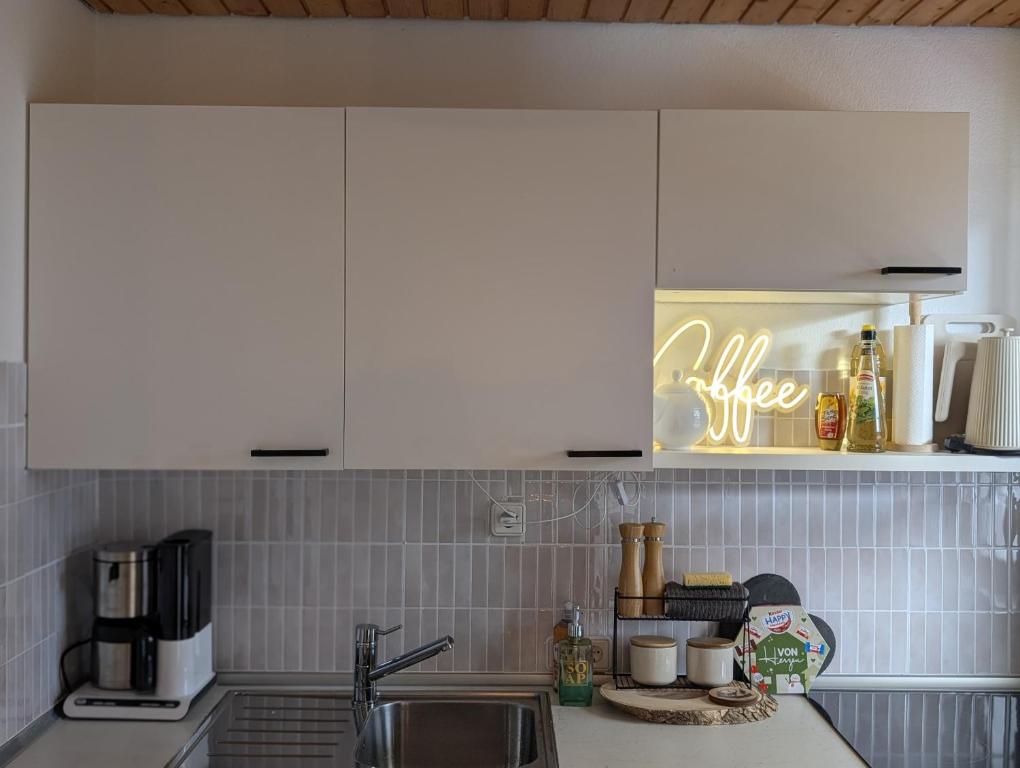 a kitchen counter with white cabinets and a sink at Apartment im Schwarzwald -Natur, Kamin & WLAN, Nähe Baiersbronn in Baiersbronn
