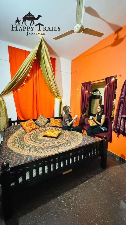 two people sitting on a bed in a room at Happy Trails Jaisalmer in Jaisalmer