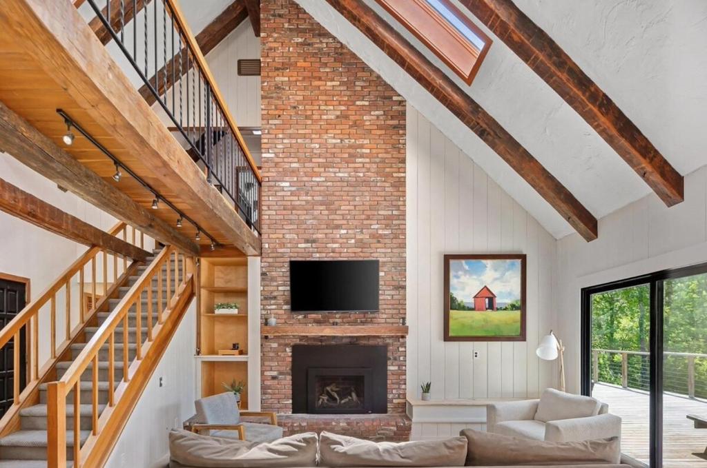 sala de estar con chimenea de ladrillo y TV en Best Location! Mountain Retreat on 7 Acres with Pond, en Stowe