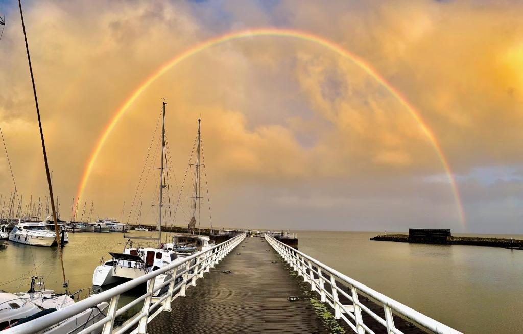 a bridge with a rainbow in the sky over boats at Slowlife in Lisbon