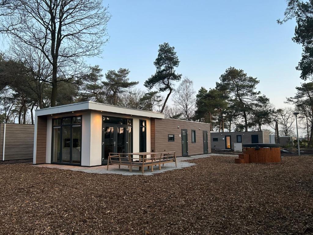 un pequeño edificio con un banco delante en Luxe chalet 5p met hottub midden in het bos - Boshuisje Casa Kuin, en Haarle
