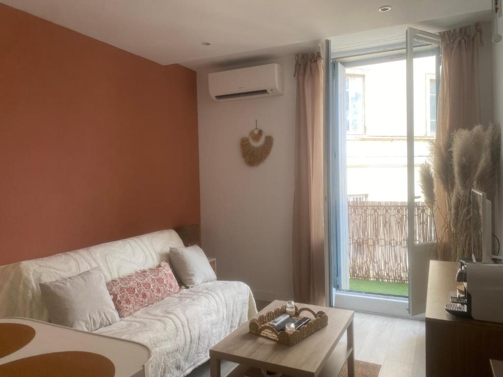 - un salon avec un canapé blanc et une fenêtre dans l'établissement Studio Blue Nimes - Centre Historique de Nimes, à Nîmes