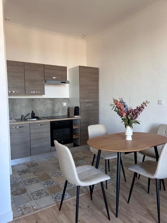 - une cuisine avec une table, des chaises et un vase de fleurs dans l'établissement Appartement chaleureux en centre ville, à Nîmes