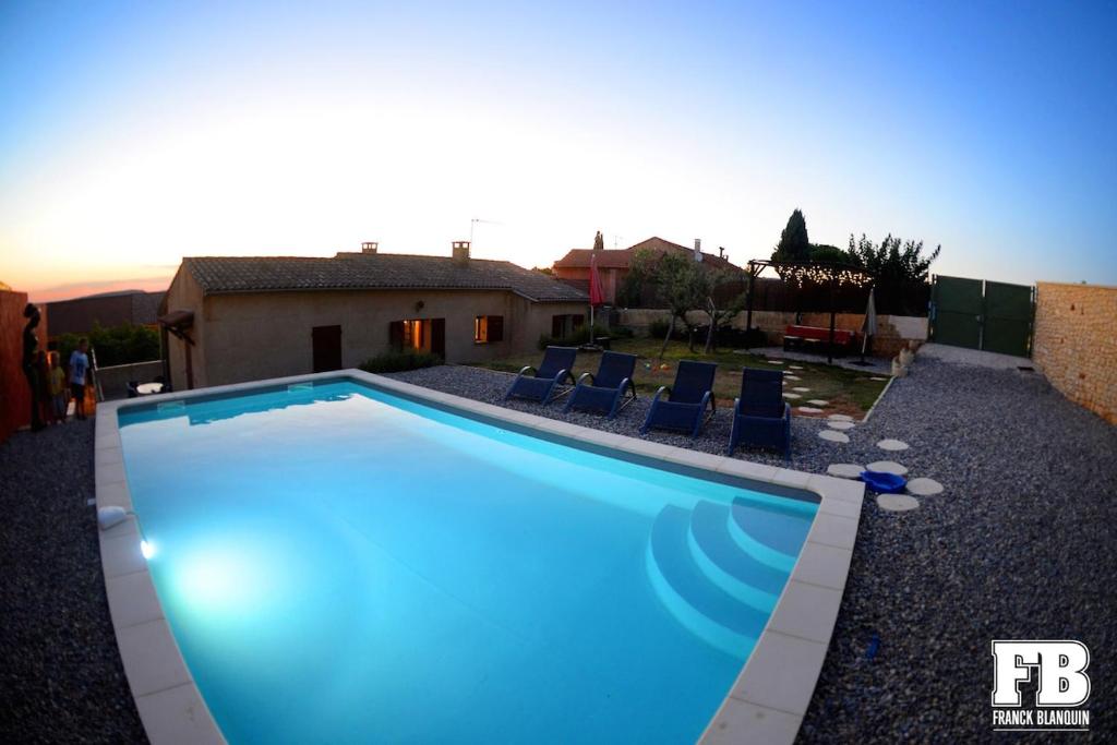 une piscine bleue avec des chaises et une maison dans l'établissement Le Jardin d'Auguste, à Roussillon