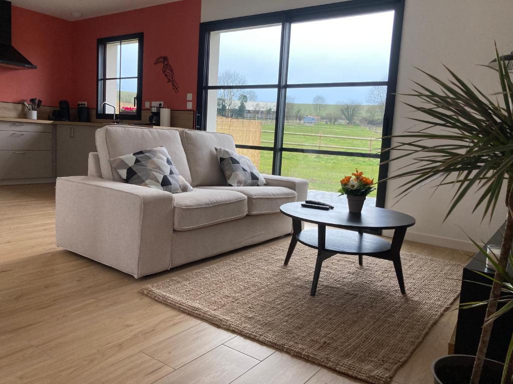 ein Wohnzimmer mit Sofa und Tisch in der Unterkunft Les Petites Maisons dans la Prairie - 2 in Maresville