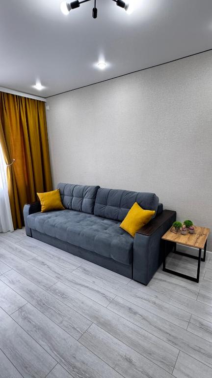 a blue couch with yellow pillows in a living room at Квартира 11 мкр 30 дом in Aktau
