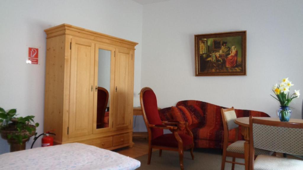 a living room with a chair and a cabinet at Pension Hans Rastatt in Rastatt