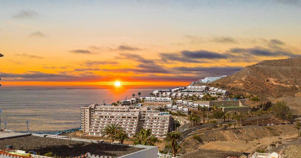 a view of a city and the ocean at sunset at Calle Goya 108 in Arguineguín