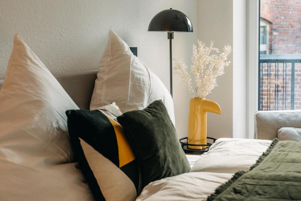 a room with pillows on a bed with a lamp at BHH Living Apartments - Zentrale Lage, ruhige Nächte, perfekter Komfort in Düsseldorf
