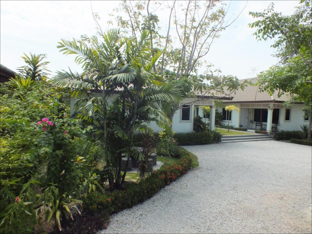 a house with a palm tree in front of a driveway at Vacation Garden Villa in Thalang