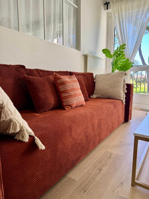 - un canapé rouge avec des oreillers dans le salon dans l'établissement Le parfum d élégance - Seignosse - Plage, à Seignosse