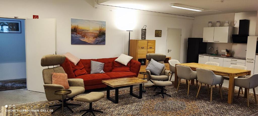 a living room with a red couch and a table at Monteur-Ferienwohnung mit 123qm bei Würzburg mit Parkplatz Terasse Grill WLAN in Veitshöchheim