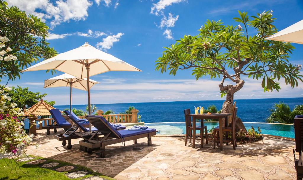eine Terrasse mit Stühlen und Tischen und Meerblick in der Unterkunft Blue Moon Villas Resort in Amed