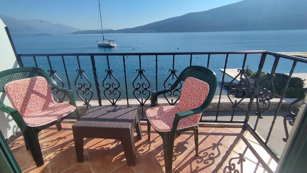 three chairs and a table on a balcony overlooking the water at Rooms Beba in Herceg-Novi