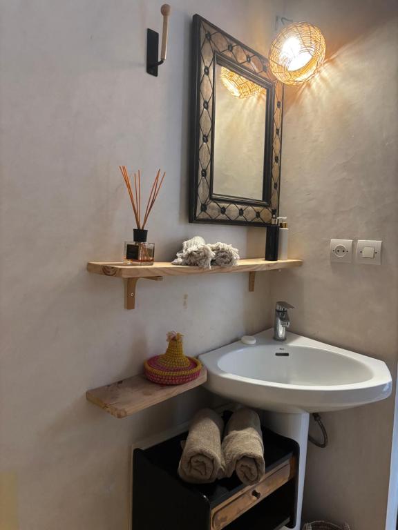 a bathroom with a sink and a mirror and towels at Maison la chèvre By Nath & Lulu in Essaouira