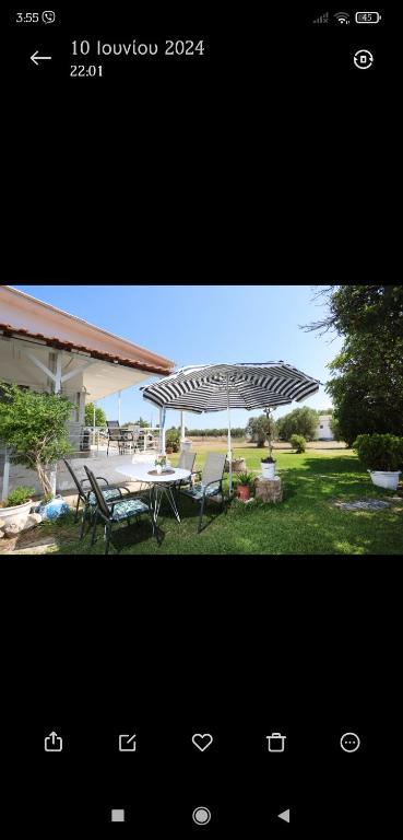 a photograph of a patio with a table and an umbrella at Family House - Παραθεριστικό Κατάλυμα in Nea Plagia