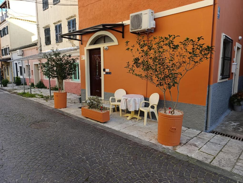 an orange building with a table and chairs on a street at Savvas&Katia's luxury studio in Mantoúkion