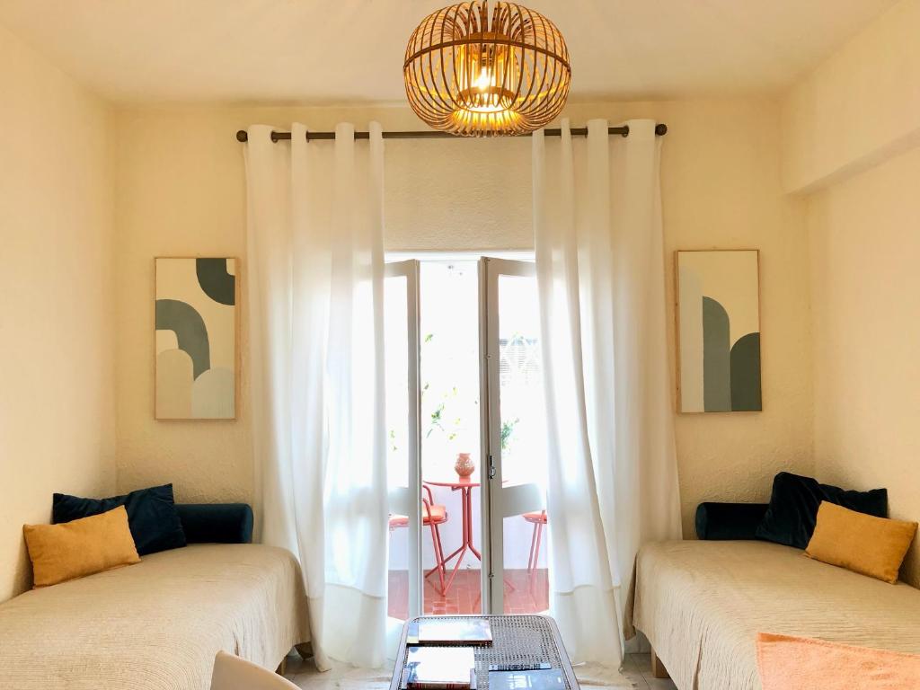 a living room with two beds and a chandelier at Apartamento a 400 metros da praia Santa Cruz in Santa Cruz