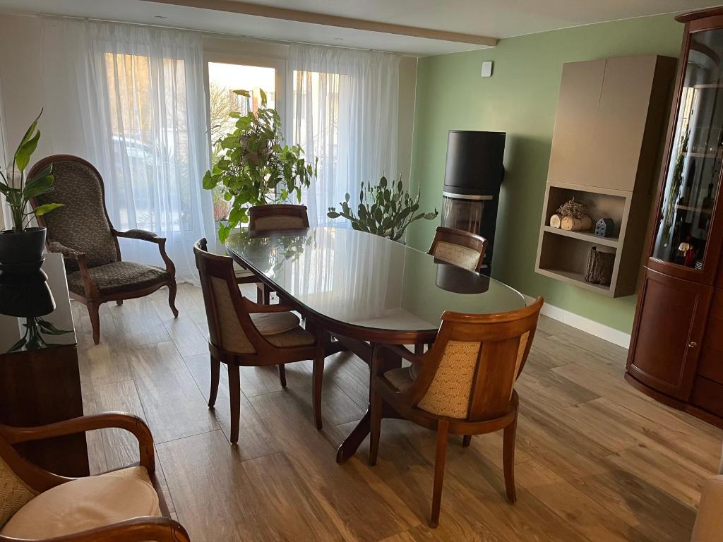 a living room with a dining room table and chairs at A l'orée de la forêt in Saint-Leu-la-Forêt