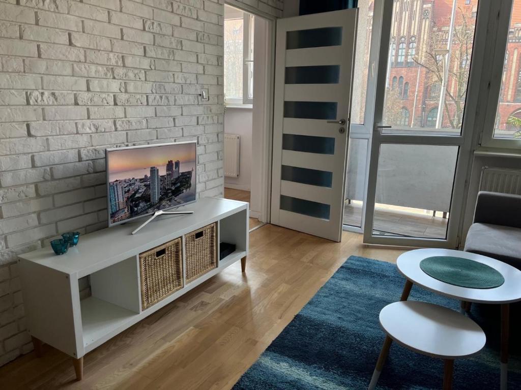 salon z telewizorem na białej ceglanej ścianie w obiekcie Apartament Turkusowy w Szczecinie