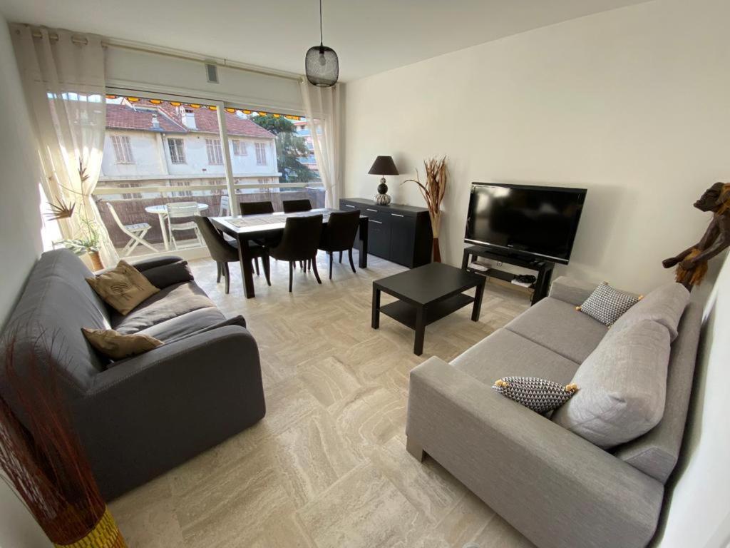 un salon avec un canapé, une télévision et une table dans l'établissement juan les pins centre proche mer 3 pièces, à Juan-les-Pins