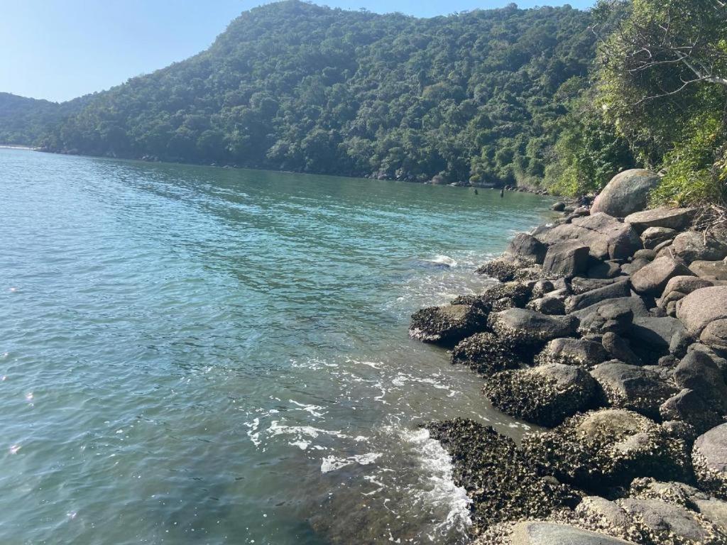 a body of water with a bunch of rocks at Apartamento com Suíte em Bertioga Indaiá 150 metros da Praia in Bertioga