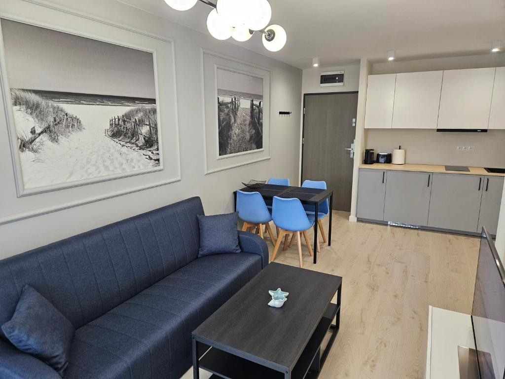 salon z niebieską kanapą i stołem w obiekcie Apartament przy plaży w mieście Niechorze
