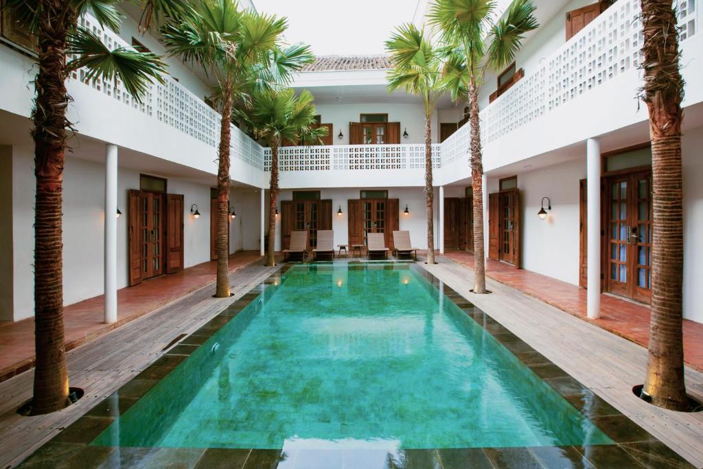 an indoor pool with palm trees in a building at Adhisthana Hotel Yogyakarta in Yogyakarta