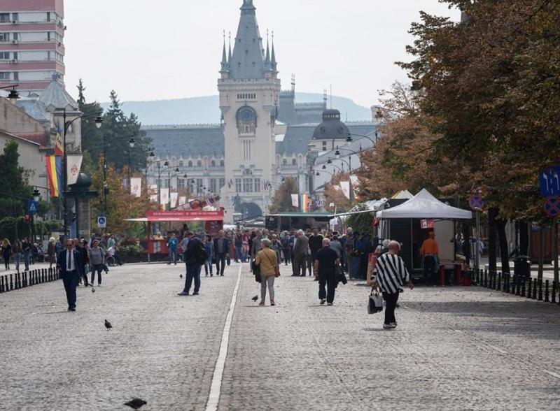 a crowd of people walking down a street with a clock tower at Cozy apartament in Iaşi