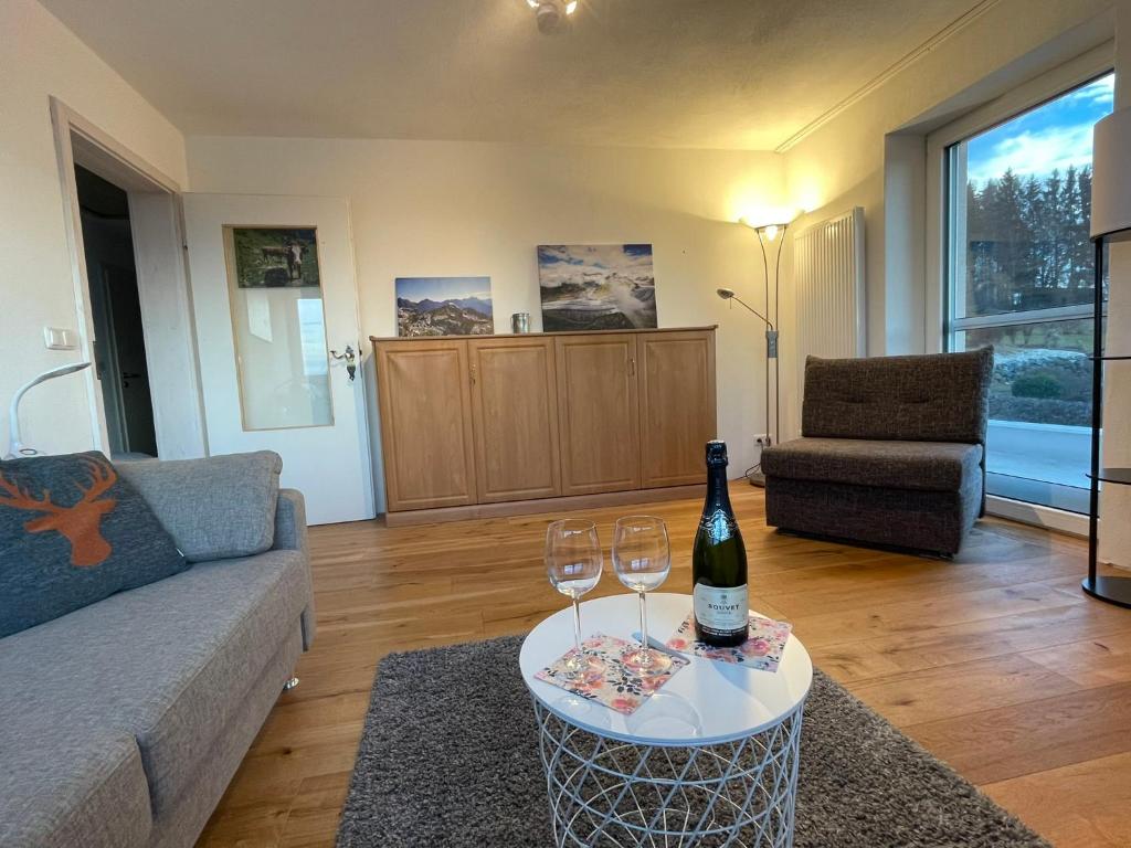 a living room with a bottle of wine and two glasses at Panorama Apartment mit 2 Schlafzi im Allgäu mit Balkon in Marktoberdorf