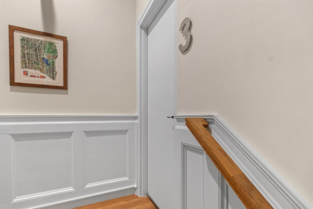 a hallway with white walls and a stairway with a clock at Heart of Adams Morgan Walk Everywhere in Washington, D.C.