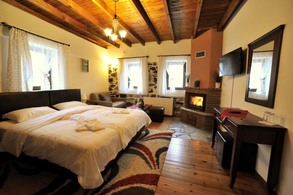 a bedroom with a bed and a living room with a fireplace at Guesthouse Papastoikou in Palaios Agios Athanasios