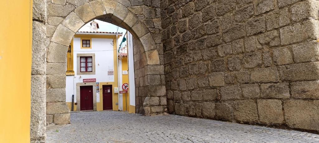 an alley with an archway in a stone wall at A Casinha do Arco, Porta da Vila in Nisa
