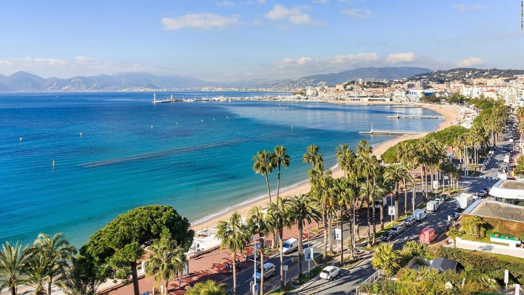 une vue sur une plage avec des palmiers et l'océan dans l'établissement 2 Bedrooms appartement entièrement rénové Cannes - 200m de la plage, à Cannes
