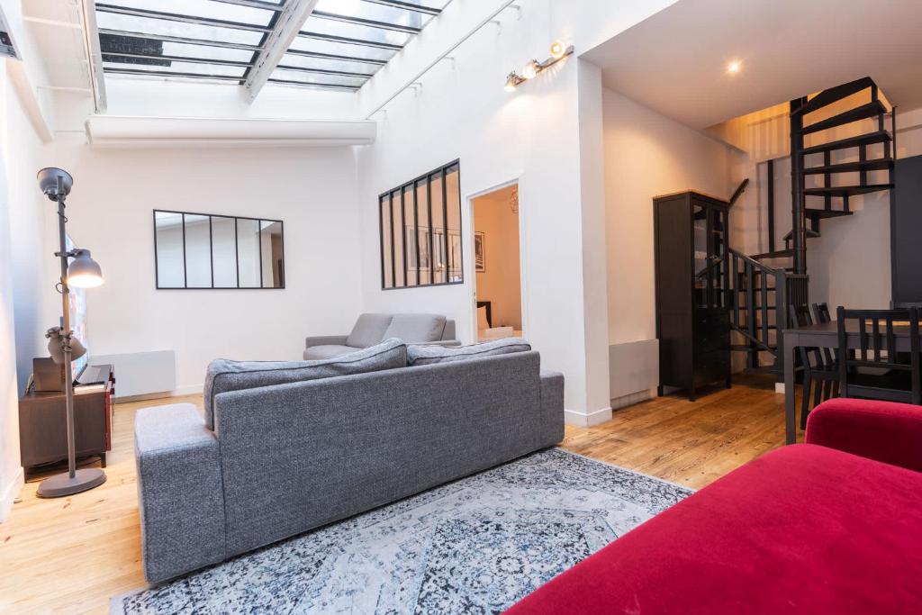 - un salon avec un canapé gris et un tapis rouge dans l'établissement Loft House 3 BR Bastille, Marais AC by LCC Agency, à Paris