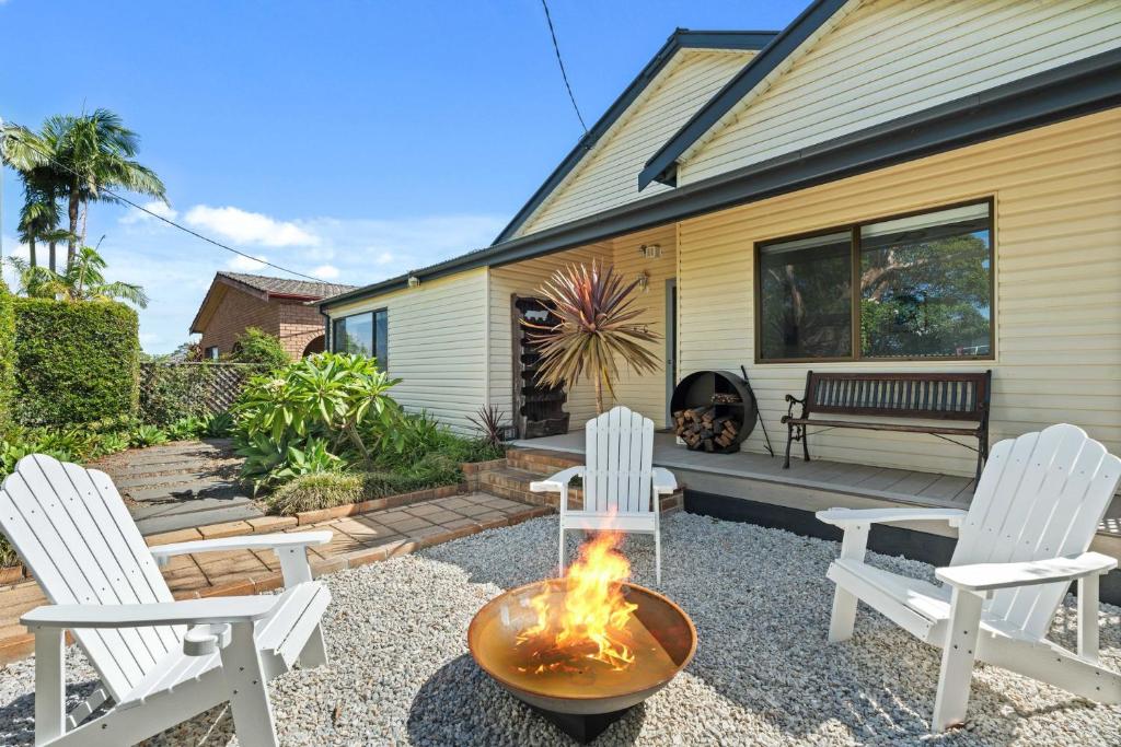 a backyard with two white chairs and a fire pit at Kingston Cottage by Experience Jervis Bay in Huskisson